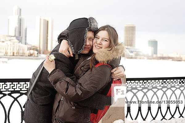 Porträt eines jungen Paares  das sich im Park an einem Geländer umarmt
