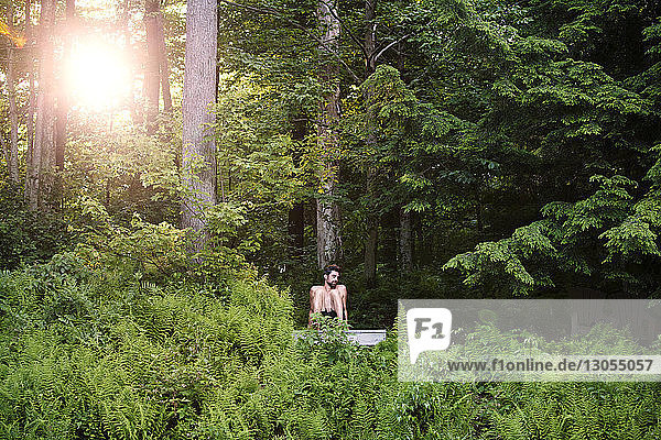 Mann entspannt sich auf Pier bei Bäumen im Wald