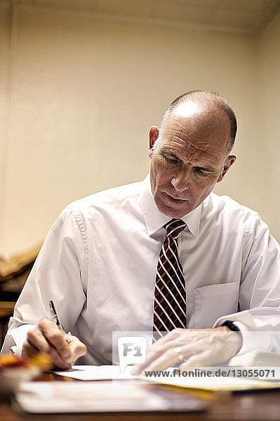 Priest writing while sitting at table