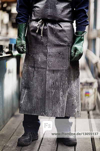 Niedriger Teil des in der Fabrik stehenden Mannes  der Arbeitsschutzkleidung trägt
