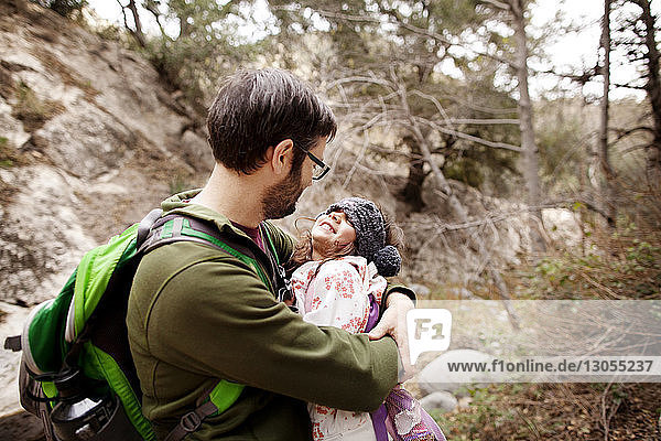Vater umarmt Mädchen im Wald
