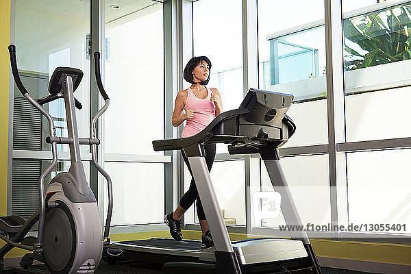 Frau  die in voller Länge auf dem Laufband im Fitnessstudio trainiert