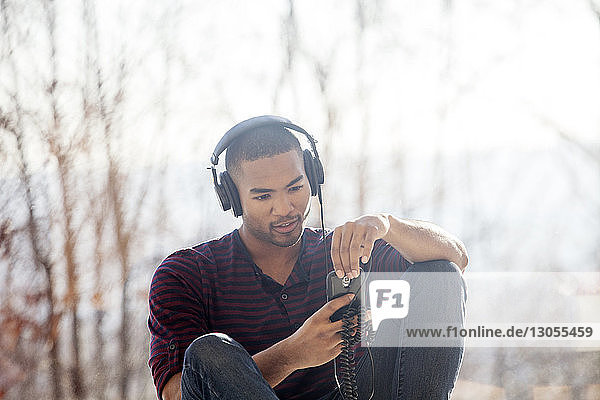 Mann hört Musik auf einem Smartphone  während er zu Hause sitzt