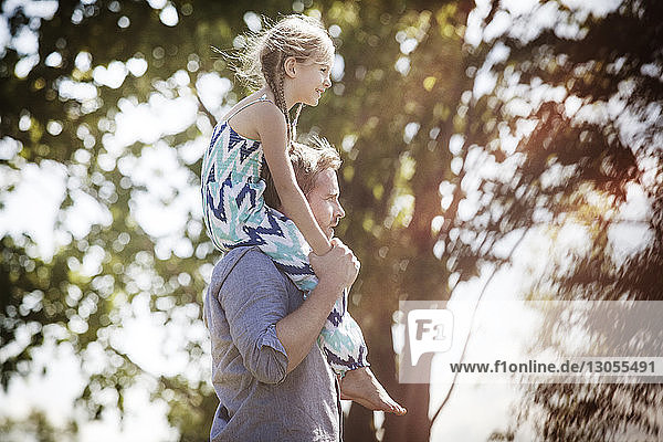 Side view of father carrying daughter on shoulder