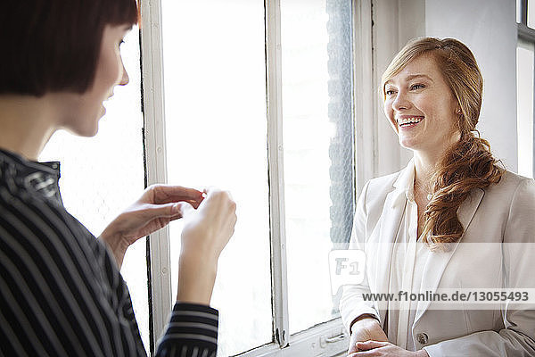 Female colleagues having discussion by window in office