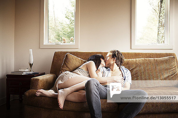 Couple kissing while relaxing on sofa