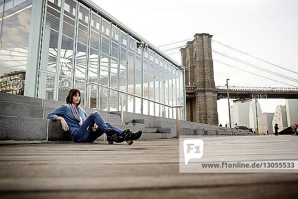 Nachdenkliche Frau sitzt am Jane's Carousel gegen die Brooklyn Bridge