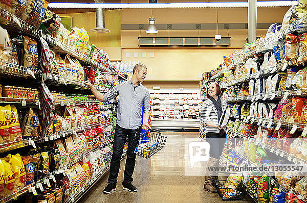 Cheerful young couple shopping in supermarket