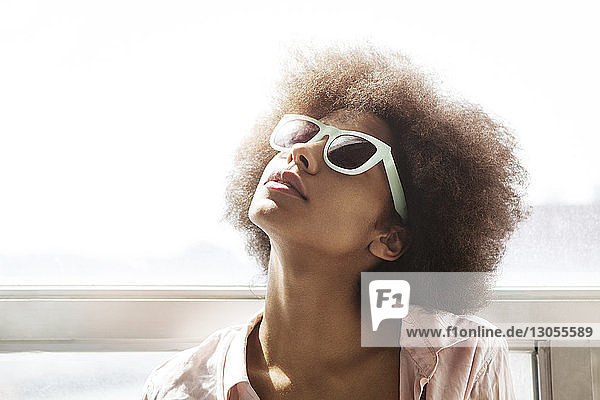 Woman with sunglasses against window at home