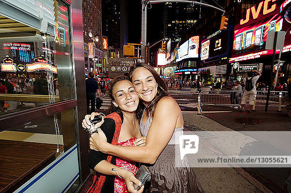 Porträt einer glücklichen Mutter  die ihre Tochter am Times Square umarmt
