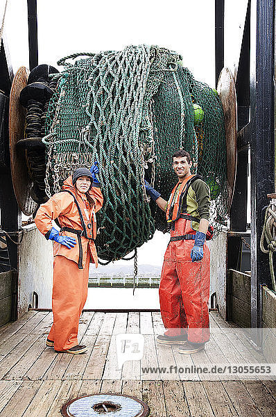 Porträt eines Mannes und einer Frau  die ein Netz halten und auf einem Fischerboot stehen