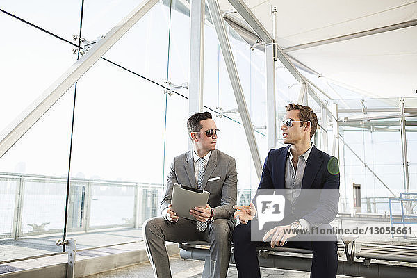 Geschäftsmann führt Diskussion  während er einen Tablet-Computer im Transportgebäude hält