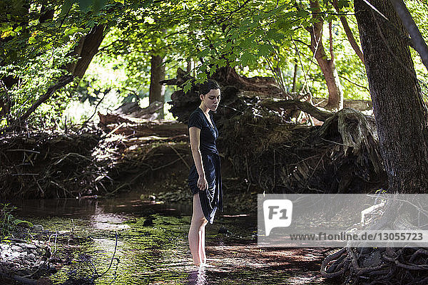 Teenage girl standing in stream at forest