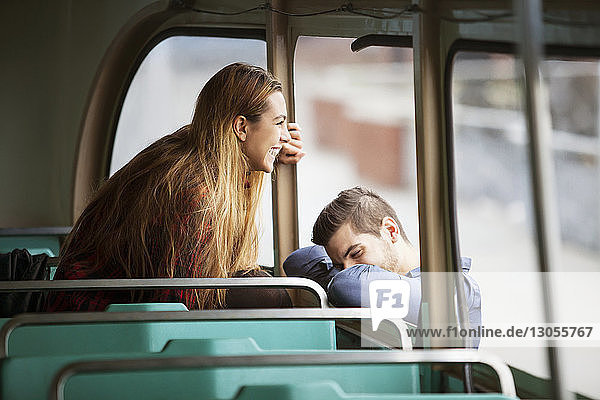 Glückliche Frau schaut durchs Fenster  während der Mann sich an die Straßenbahn lehnt