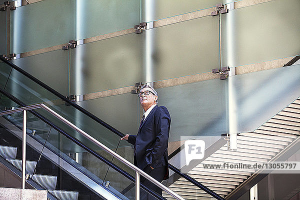 Confident businessman standing on escalator