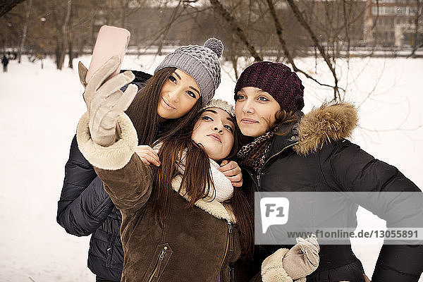 Woman taking selfie with friends on field during winter