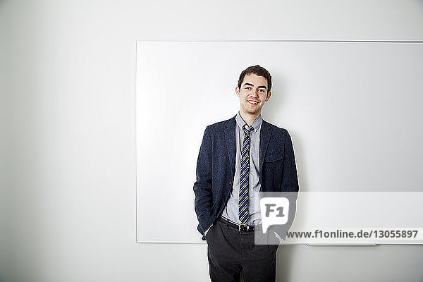 Portrait of businessman standing against whiteboard