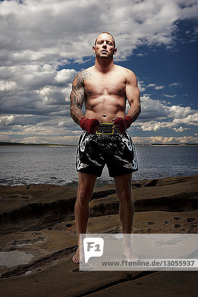 Portrait of male boxer standing at beach