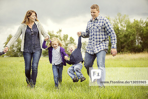 Happy children with parents enjoying on grassy field