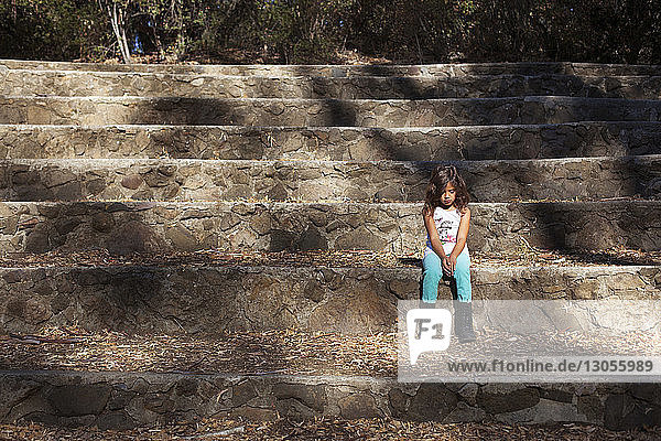 Sad girl sitting on stone staircase