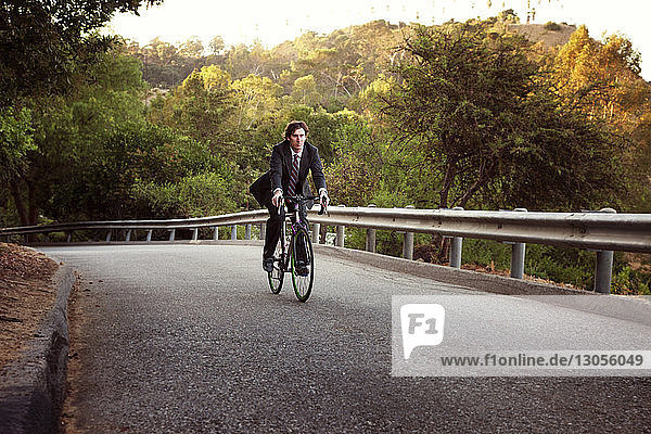 Businessman riding bicycle on road