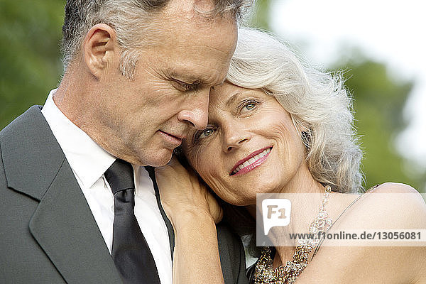Close-up of happy senior woman resting on man's shoulder
