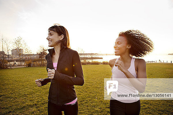 Entschlossene Freundinnen joggen im Park bei klarem Himmel