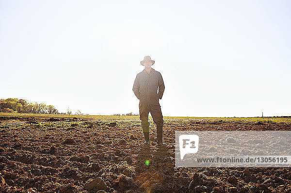Porträt eines selbstbewussten Bauern  der an einem sonnigen Tag vor klarem Himmel auf dem Feld steht