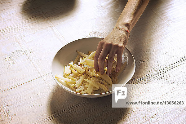Ausgeschnittenes Bild einer Hand  die Pommes frites nimmt