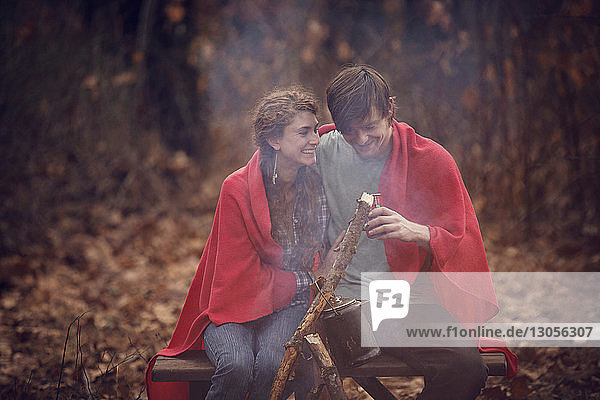 Glückliches Paar sitzt auf Bank im Wald