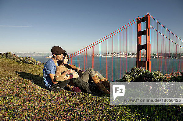 Junges Paar entspannt sich auf dem Spielfeld gegen die Golden Gate Bridge