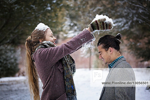 Woman putting snow on boyfriend's head at forest