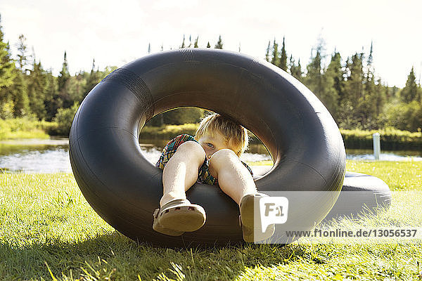 Junge spielt mit aufblasbarem Ring auf Grasfeld