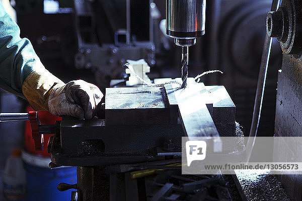 Cropped image of worker operating drill machine at workshop