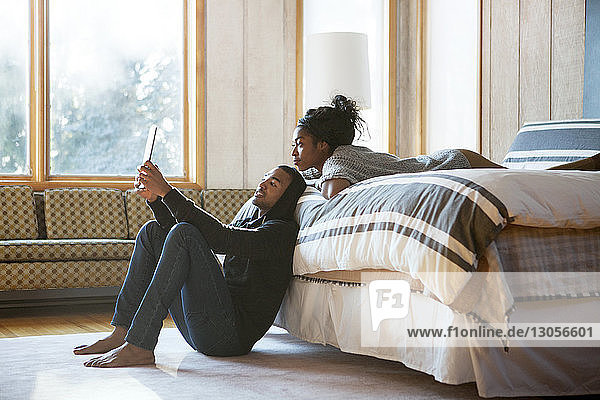Ehepaar betrachtet Tablet-Computer  während es sich im Schlafzimmer entspannt