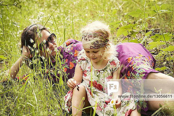 Mädchen sitzt mit Mutter auf Grasfeld