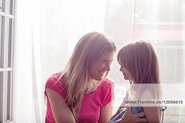 Nahaufnahme einer glücklichen Mutter  die ihre Tochter am Fenster betrachtet