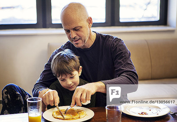 Vater und Sohn essen Pfannkuchen  während sie am Tisch sitzen