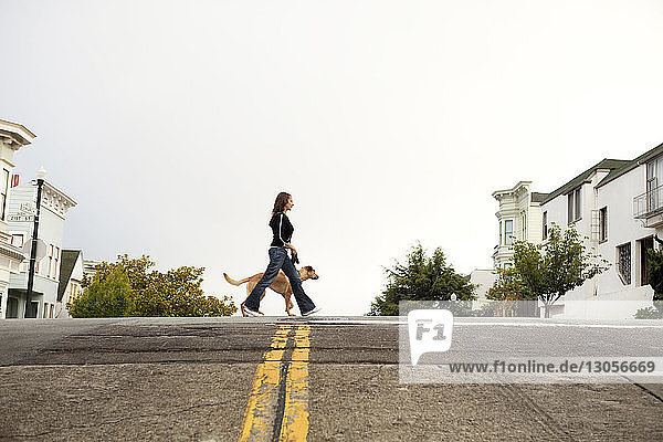 Seitenansicht von Frau und Hund beim Spaziergang auf der Straße