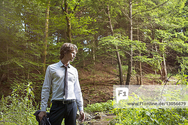 Man looking away while standing in forest