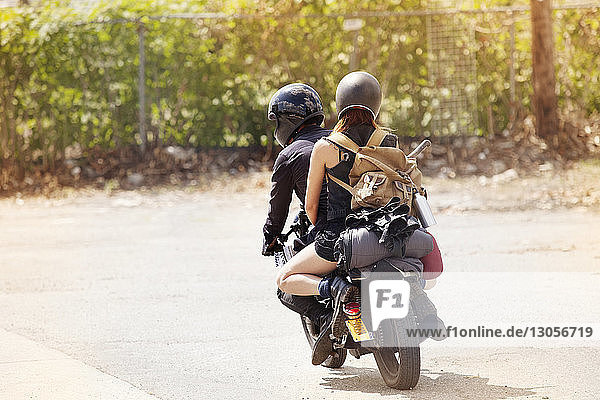 Rückansicht eines auf einem Motorrad fahrenden Paares