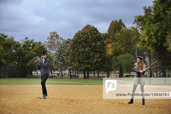 Glückliches Paar spielt Baseball auf dem Spielfeld gegen den Himmel