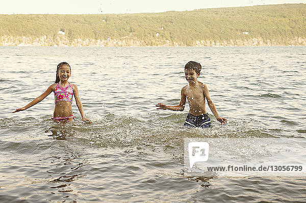 Siblings splashing water in lake