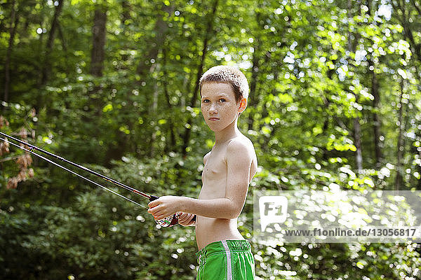 Side view of boy fishing in forest