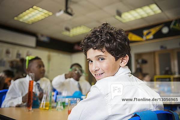 Portrait of smiling boy sitting at table in laboratory