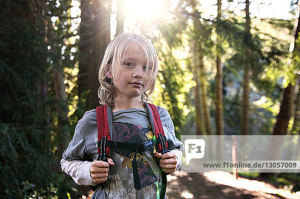 Portrait of boy with backpack standing in forest