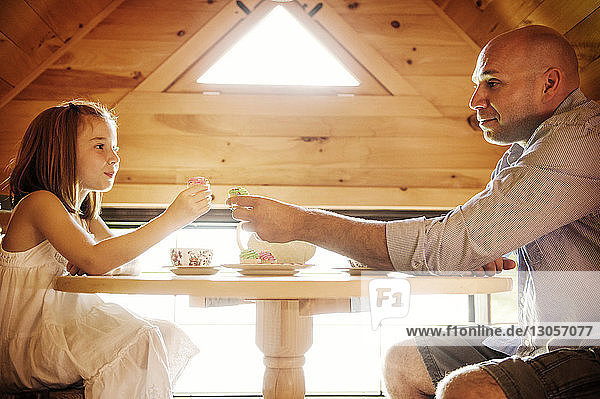 Vater und Tochter halten Muffins  während sie am Tisch sitzen