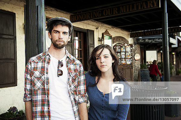 Portrait of couple standing against building
