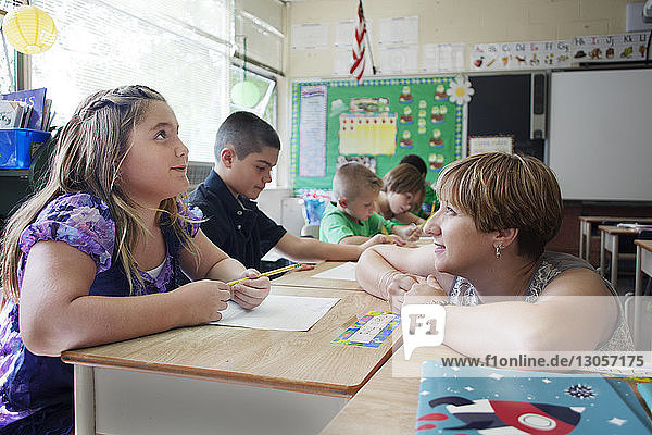 Lehrerin betrachtet Kinder beim Lernen in der Schule
