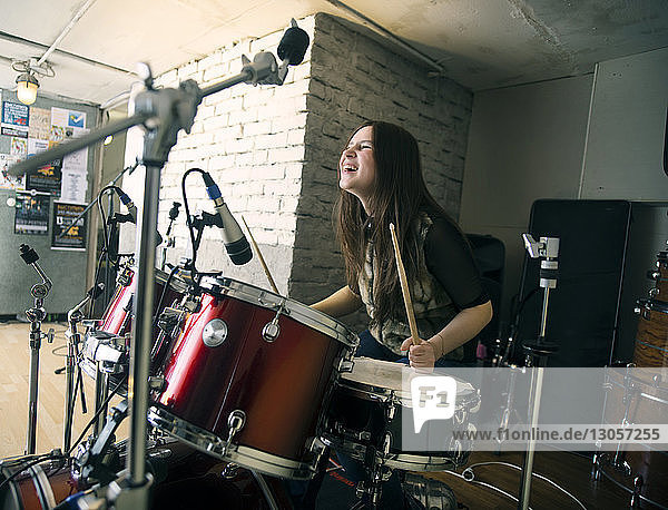 Fröhliche Frau genießt es  zu Hause Schlagzeug zu spielen